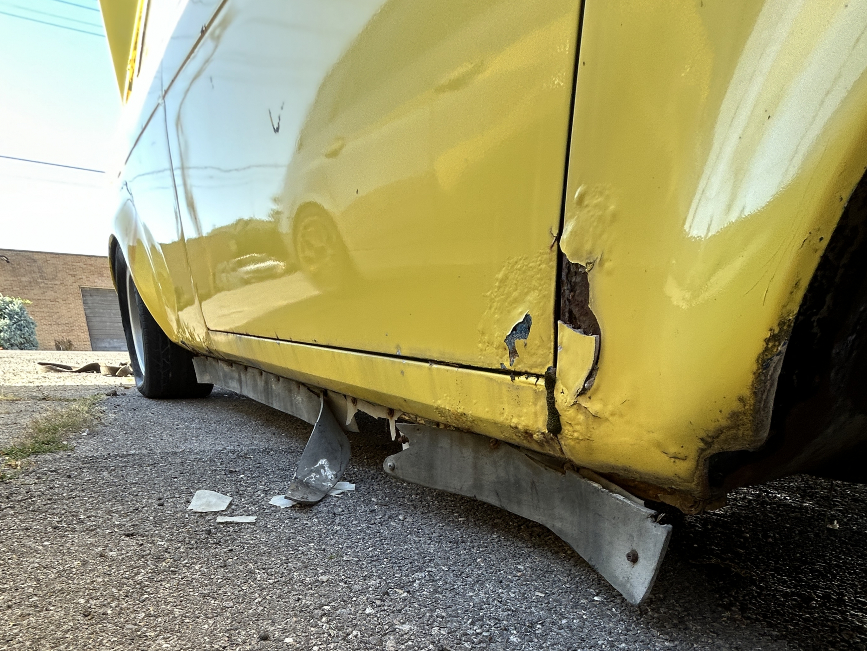 Detail of body filler and rust on a yellow datsun 510